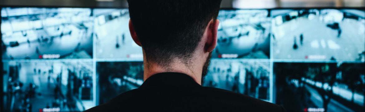 Man in front of computer screens conducting real time security monitoring